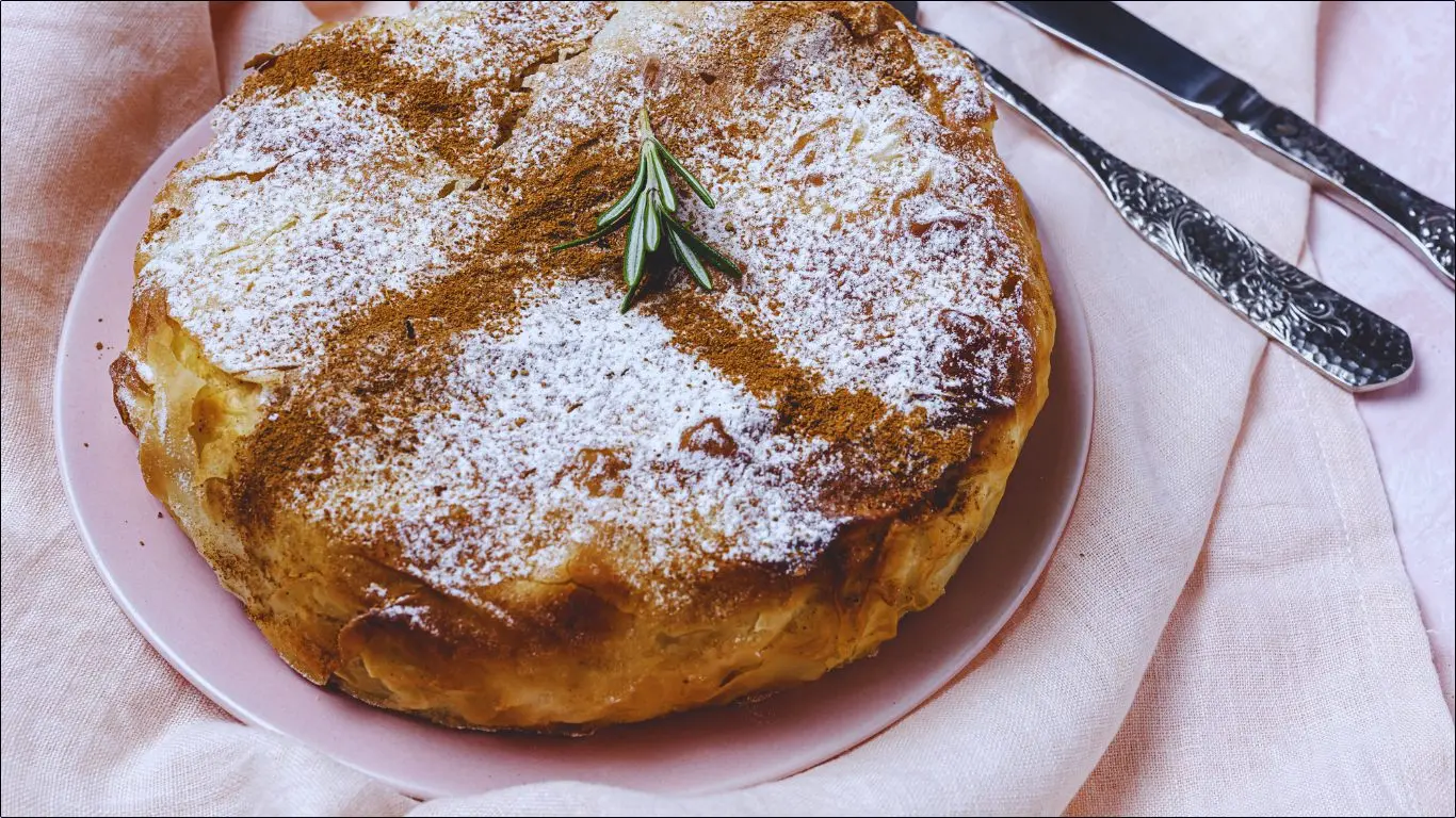 Golden Chicken Pastilla topped with powdered sugar and filled with spiced shredded chicken and almonds