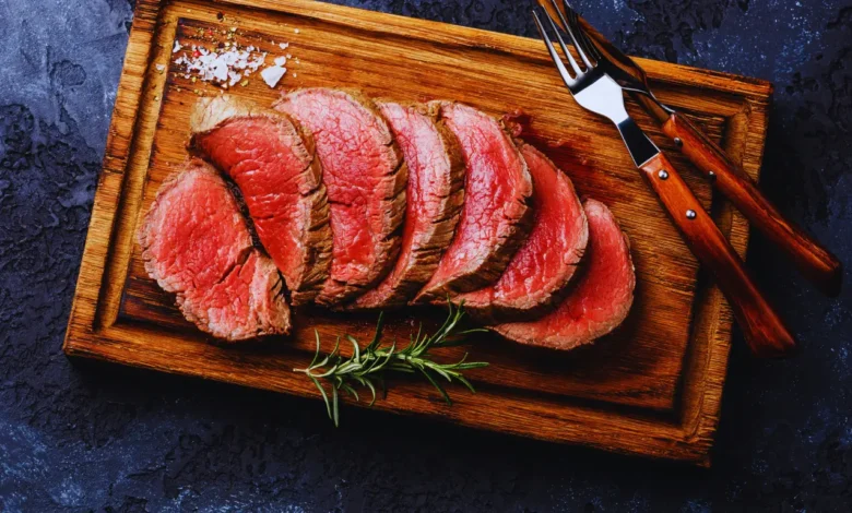 Juicy and tender beef tenderloin roast, perfectly seasoned with garlic, rosemary, and thyme, sliced and served with roasted vegetables and potatoes.